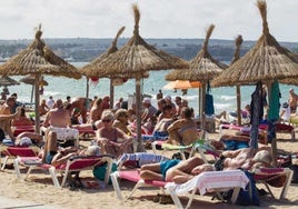 Numerosos turistas tomando el sol en una playa.