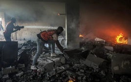 Dos rescatistas trabajan entre los escombros de un edificio atacado esta madrugada por la aviación hebrea en Gaza City.
