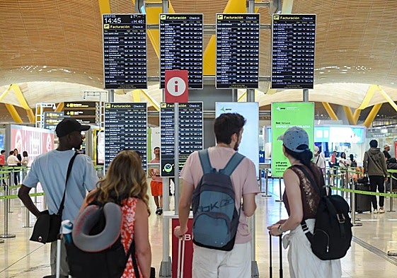 Pasajeros observan el panel de llegadas y salidas, en Barajas
