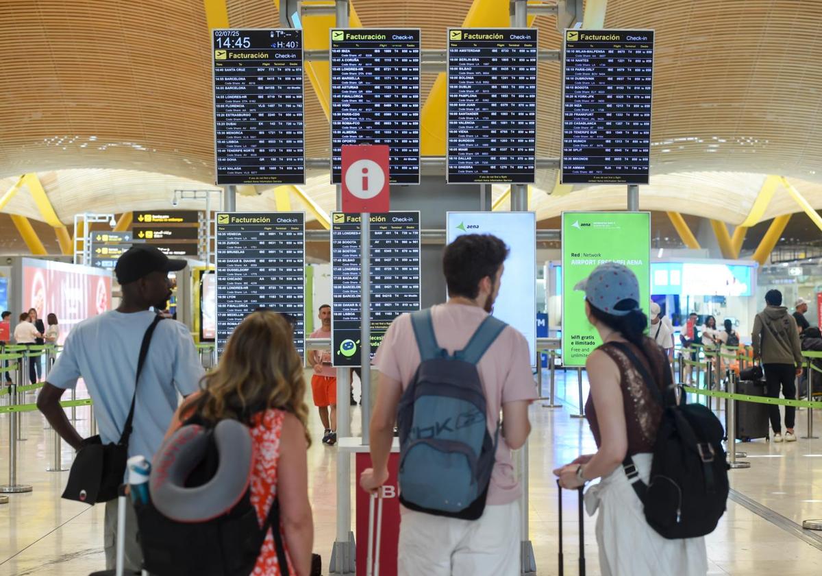 Pasajeros observan el panel de llegadas y salidas, en Barajas
