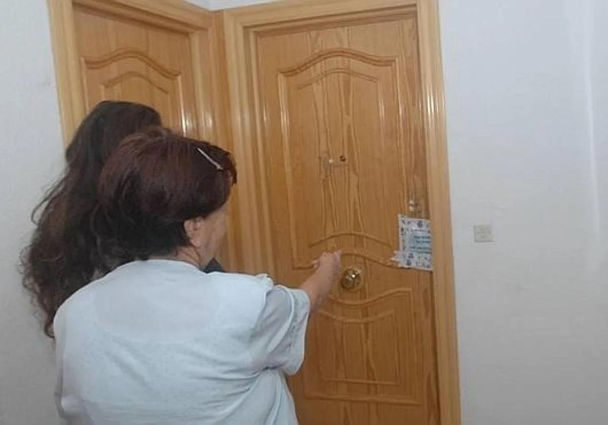 Una vecina señala la puerta de la vivienda de la víctima, precintada por la Policía