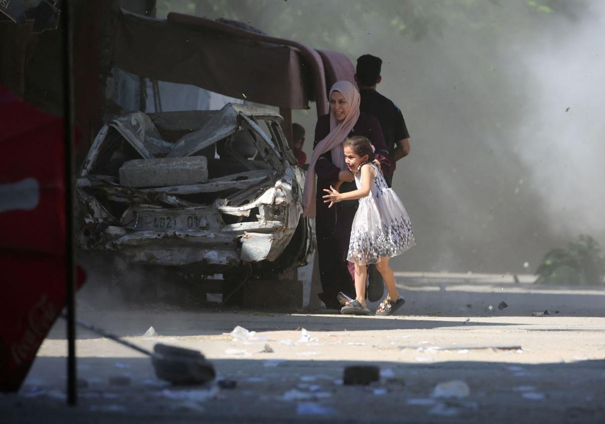 Una madre y su hija corren a refugiarse durante un ataque israelí en el campamento de Al-Bureij, en el centro de Gaza.