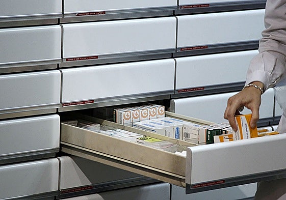 Una farmacéutica coloca medicamentos en uno de los cajones de la botica.