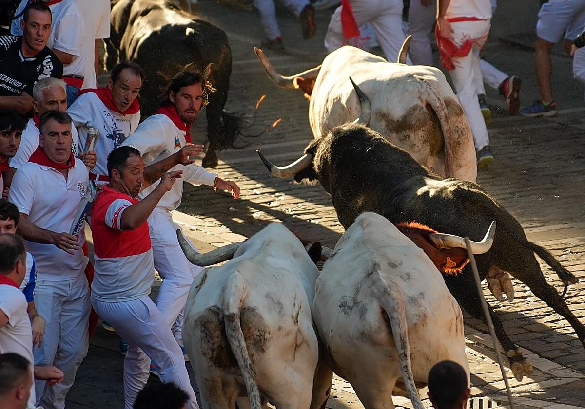 Los mozos son perseguidos por toros de la ganadería Victoriano del Río Cortés durante el cuarto encierro de los Sanfermines, este jueves, en Pamplona.