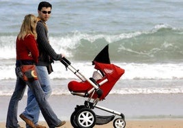 Una pareja pasea por la playa con su hijo.