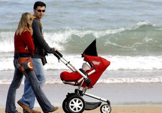 Una pareja pasea por la playa con su hijo.