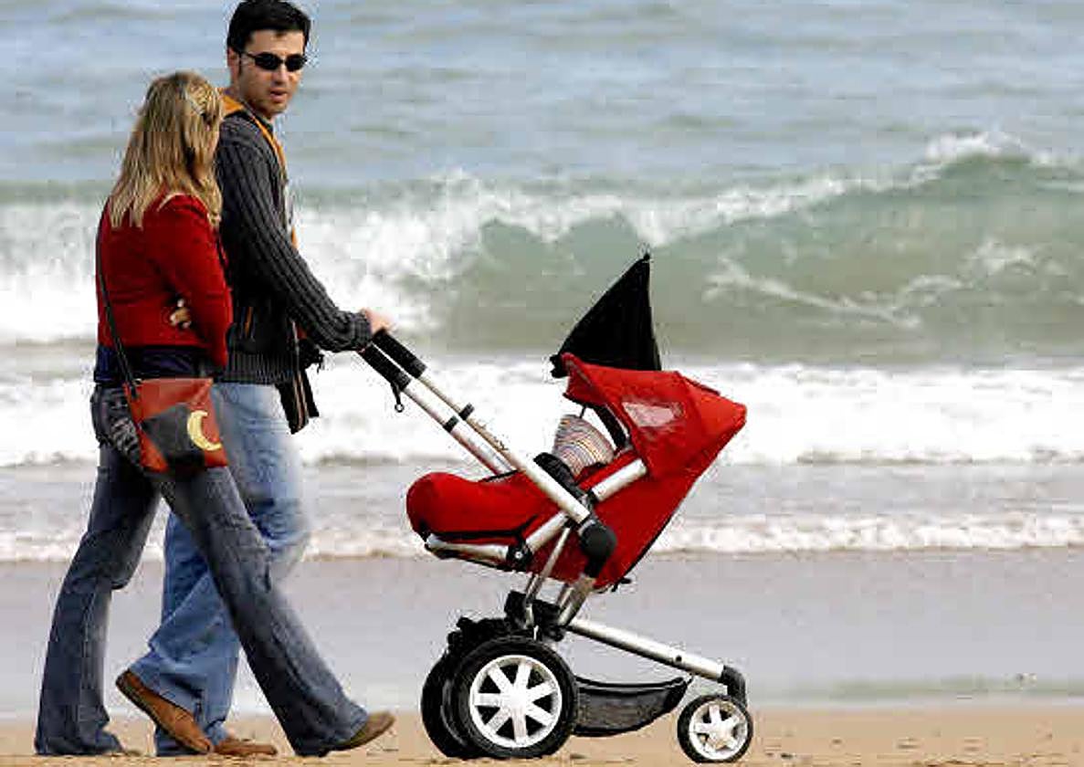 Una pareja pasea por la playa con su hijo.