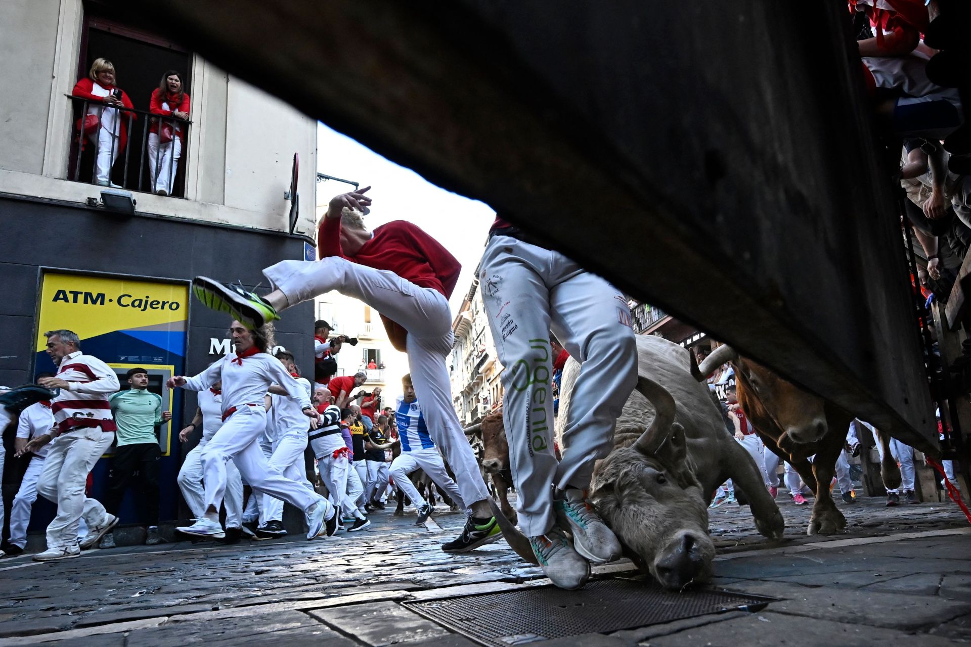 Varios mozos resbalan en la curva de la calle Estafeta perseguidos por los toros de la ganadería Álvaro Núñez durante el tercer encierro.