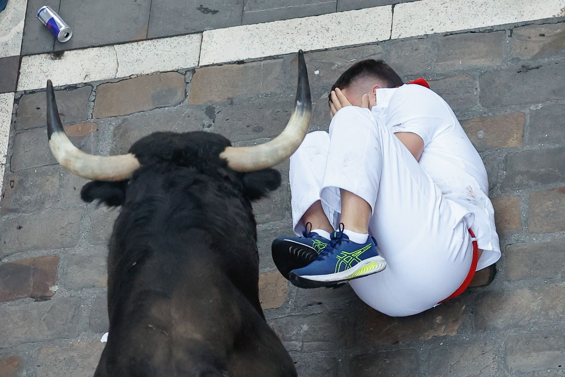 Un mozo se protege tras caer al paso de los toros de la ganadería Victoriano del Río Cortés durante el cuarto encierro de los Sanfermines, este jueves.