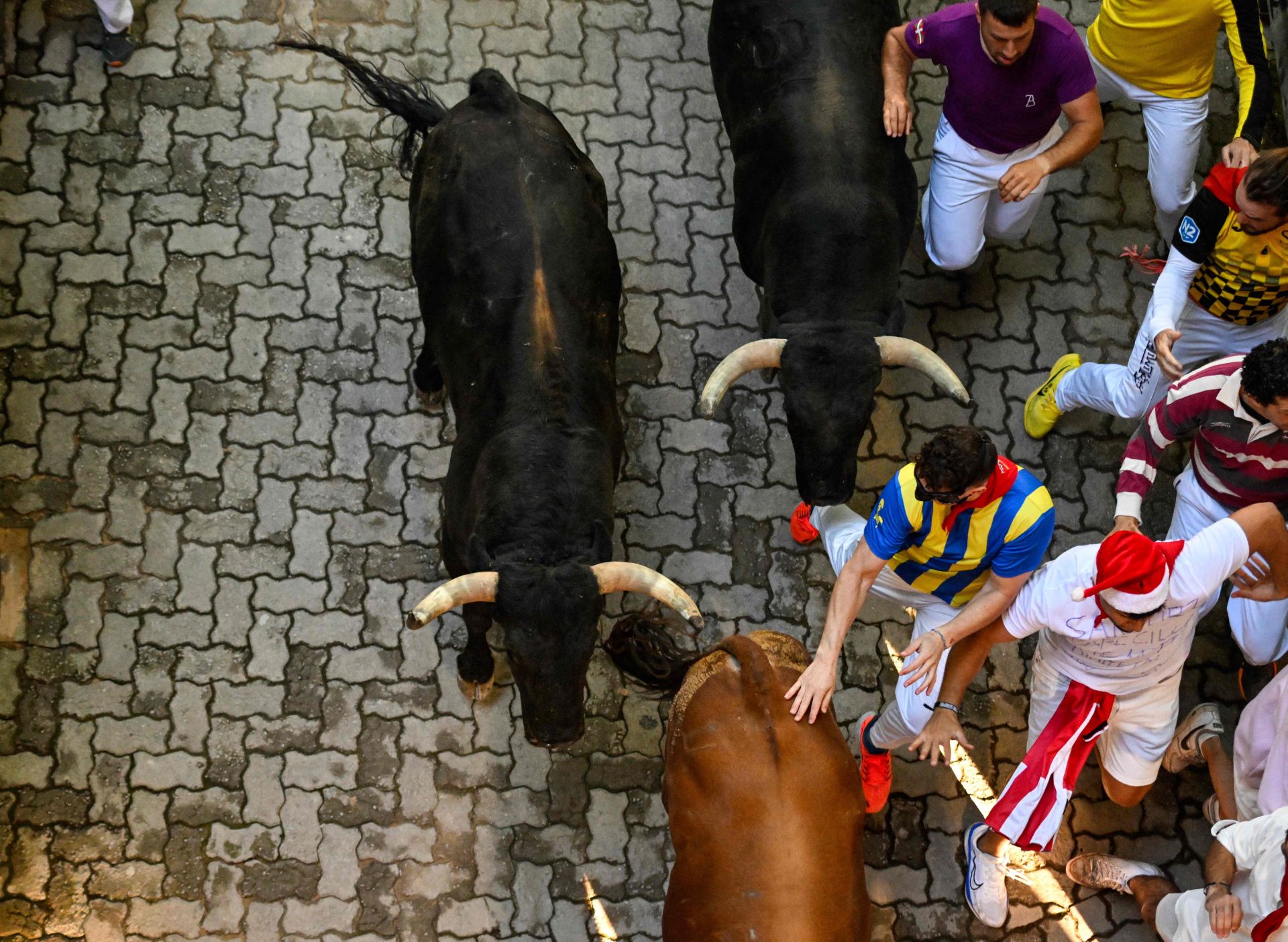 Varios mozos corren delante de los toros de Victoriano del Río durante el cuarto encierro de San Fermín en Pamplona