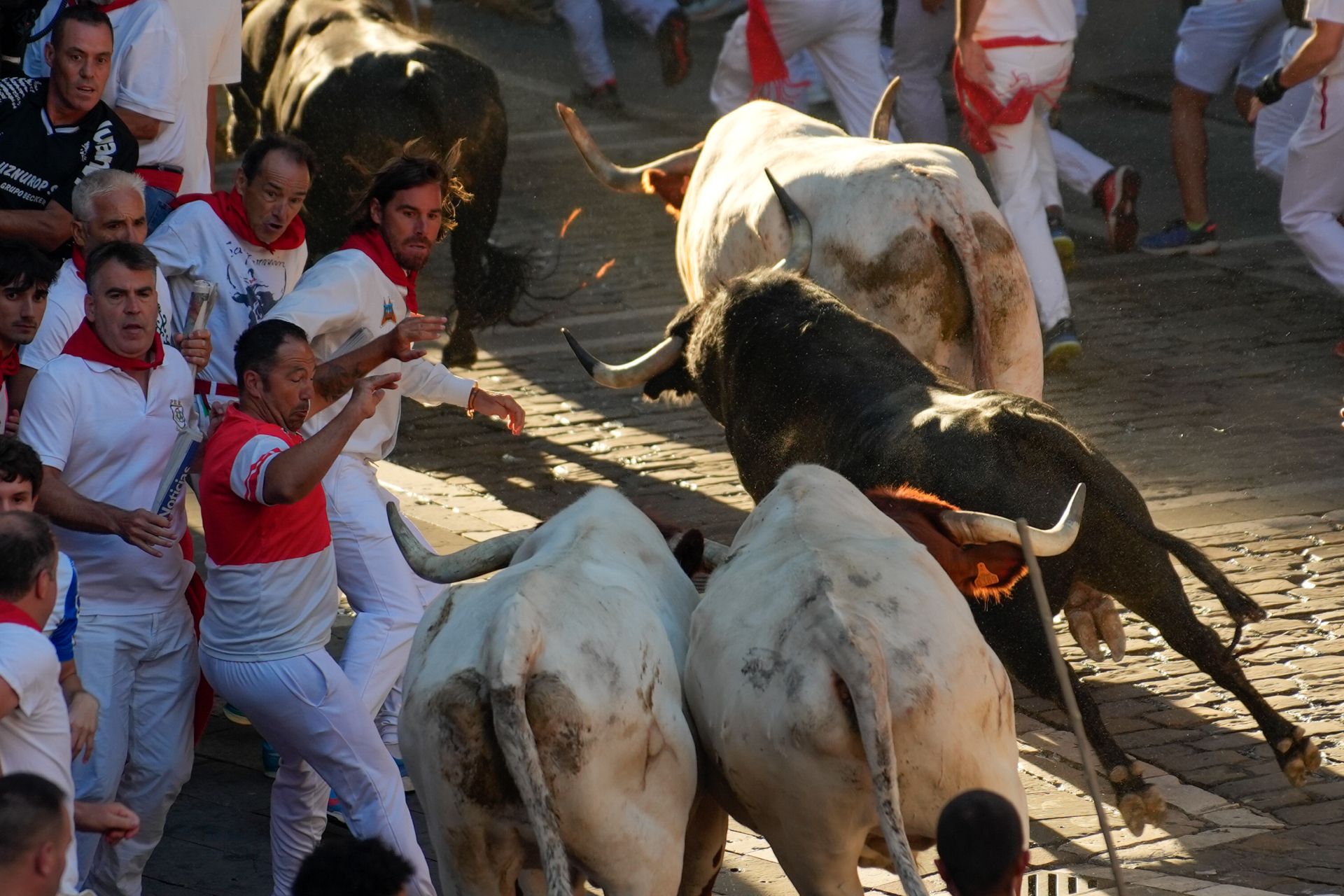 Los mozos son perseguidos por toros de la ganadería Victoriano del Río Cortés durante el cuarto encierro de los Sanfermines, este jueves, en Pamplona.