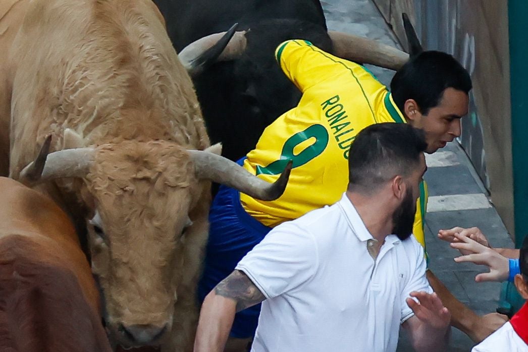 Uno de los mozos sale despedido hacia la pared ras toparse con uno de los toros de la ganadería Jandilla durante el quinto encierro de los Sanfermines.