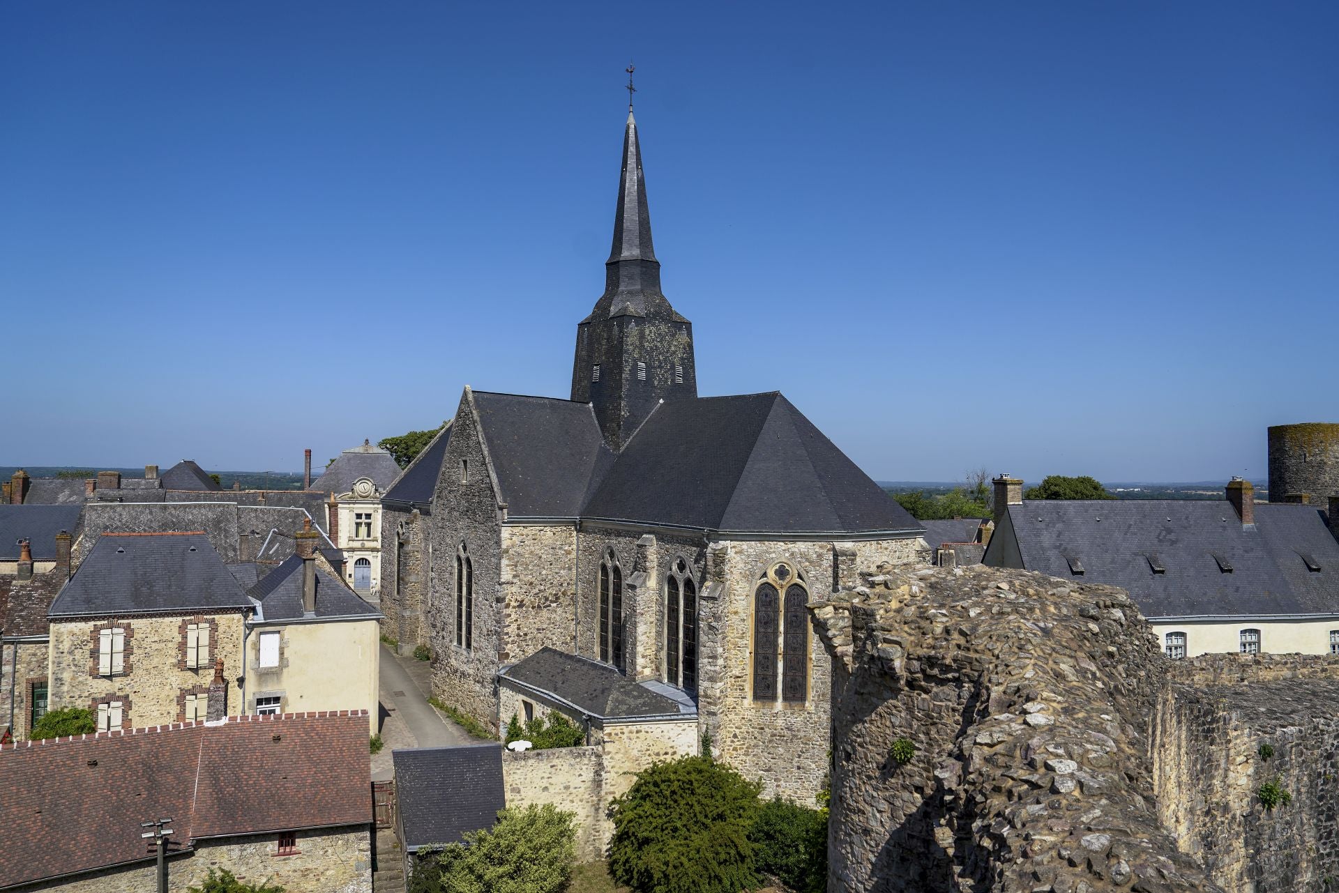 Imagen secundaria 1 - Arriba, detalle de un letrero con una figura de las cartas del tarot. A la izquierda, vistas del pueblo desde lo alto del castillo. A la derecha, la senda extramuros conocida como 'le promenade de la Poterne' que rodea el pueblo de Sainte Suzanne.