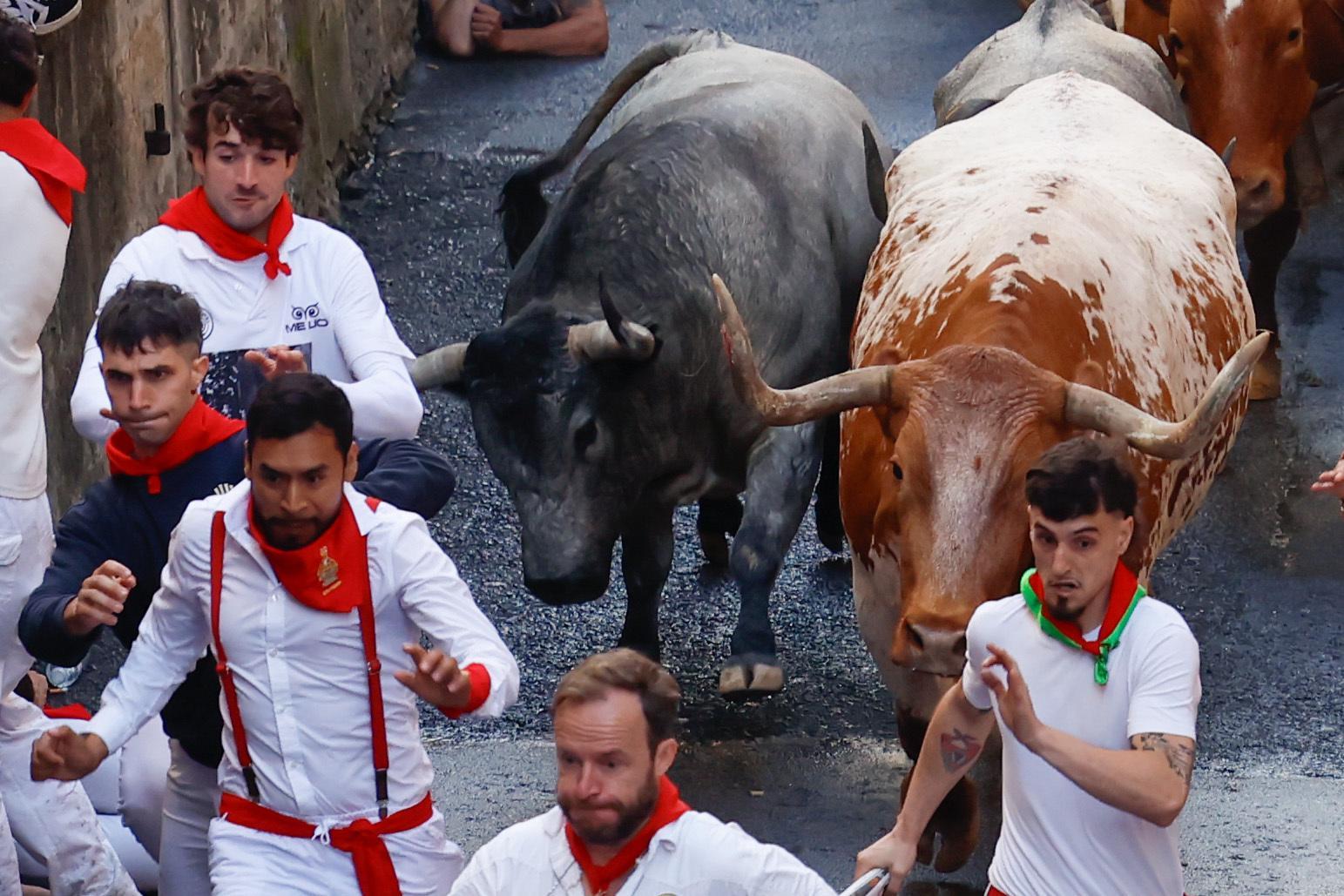 Varios corredores perseguidos por dos de los toros.