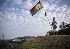 Una mujer ondea una bandera autóctona de Nueva Caledonia en Numea, la capital.