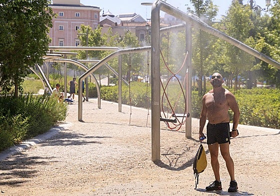 Un viandante se refresca en un difusor de agua situado en la Plaza de España en Madrid.