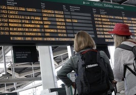 Viajeros observan los horarios de las salidas de los trenes.