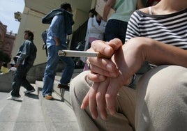 Una joven fumando un cigarrillo en las escaleras de la Facultad de Medicina