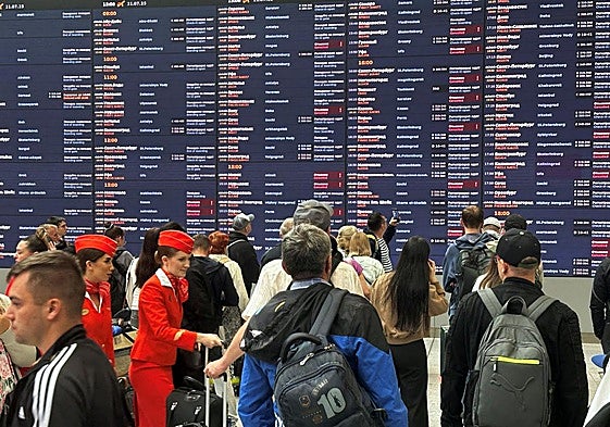 Pasajeros observan el panel de información después de que muchos vuelos fueron cancelados o retrasados debido a los ataques con drones ucranianos, en el aeropuerto internacional Sheremetyevo en las afueras de Moscú.