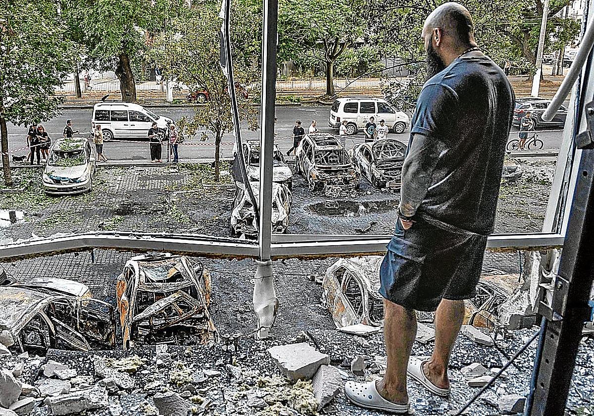 Un hombre mira desde una ventana rota de un edificio dañado tras un ataque con drones en Odesa.