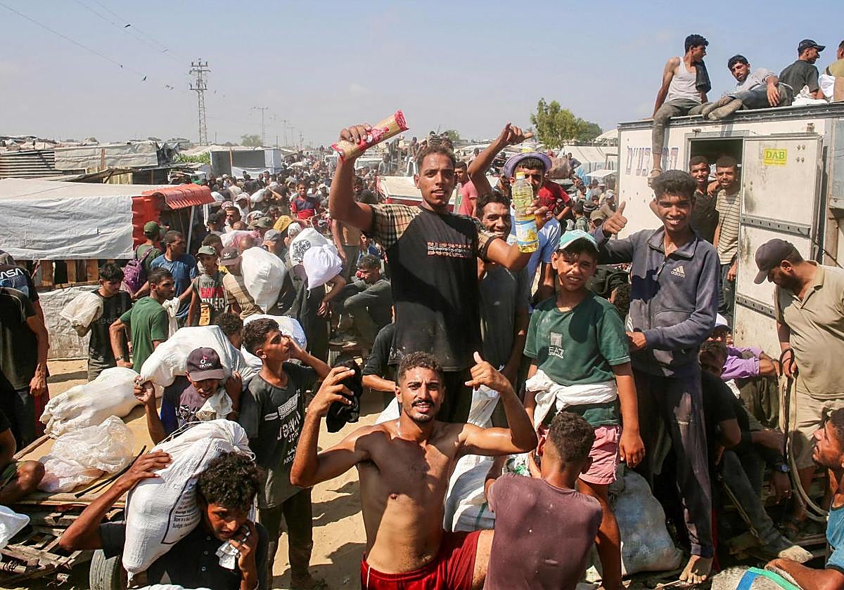 Un grupo de gazatíes celebra el reparto de comida en el campamento de Al-Mawasi, en Rafah.