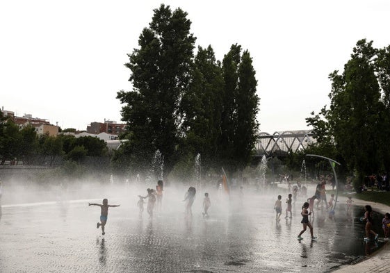 Un grupo de niños juega y se refresca en un parque de Madrid.