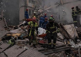 Los bomberos rescatan un cuerpo de entre los escombros de un edificio residencial destruido por un misil este jueves en Kiev.
