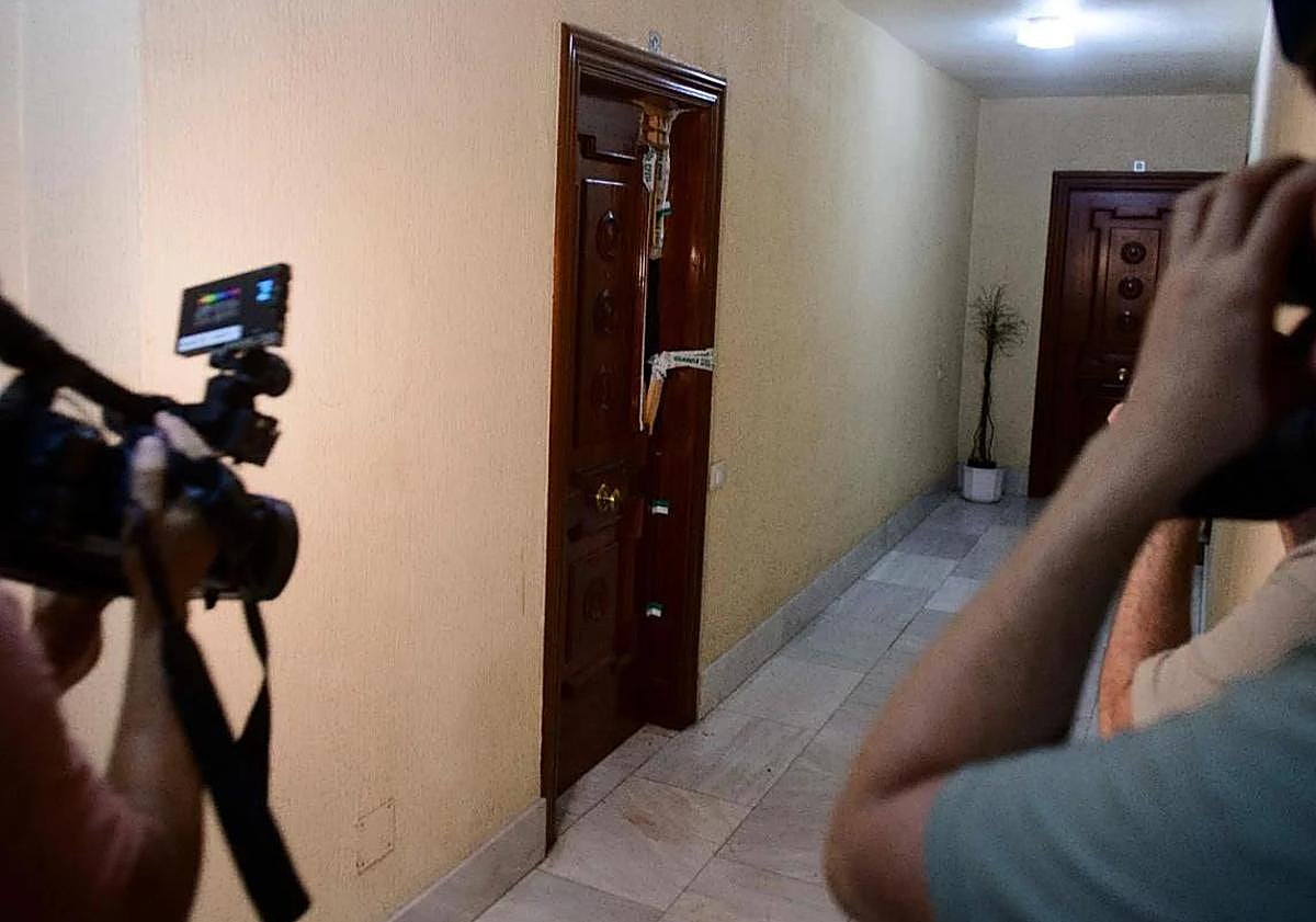 Imagen principal - Arriba, la puerta de la casa donde se encontró el cadáver. Abajo, agentes en la entrada del edificio.