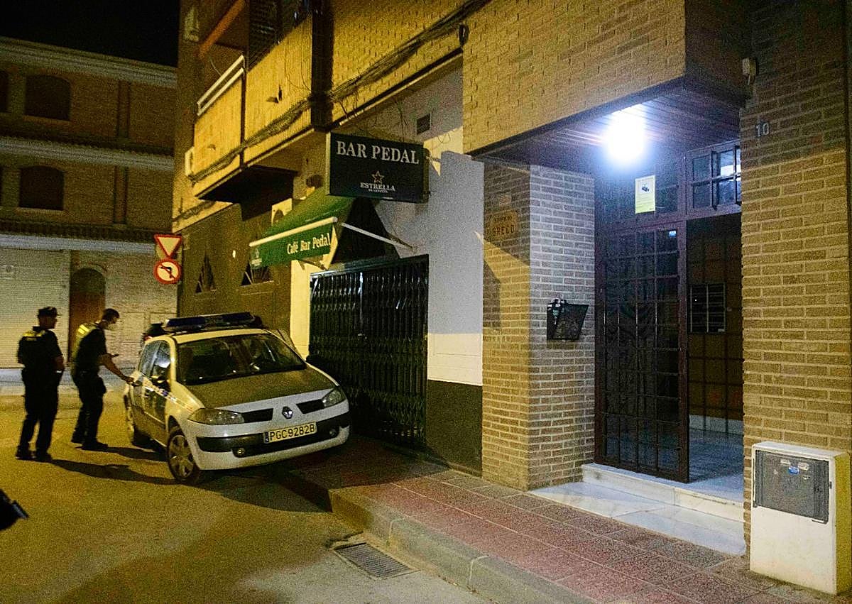 Imagen secundaria 1 - Arriba, la puerta de la casa donde se encontró el cadáver. Abajo, agentes en la entrada del edificio.
