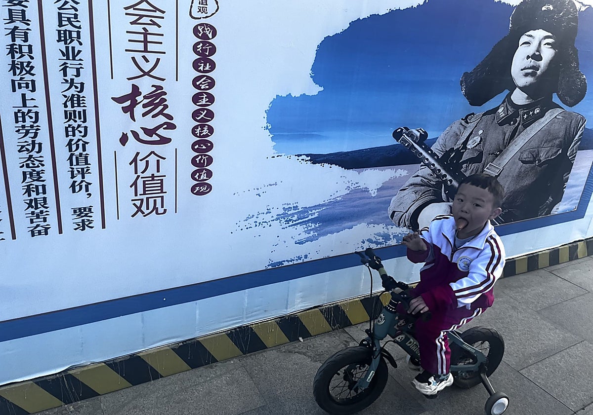 Imagen principal - Un crío con su triciclo ante un cartel político ante las calles en Lhasa. La imagen de Xi Jinping en los autobuses, y una presentación en la feria FamTrip de Pekin.