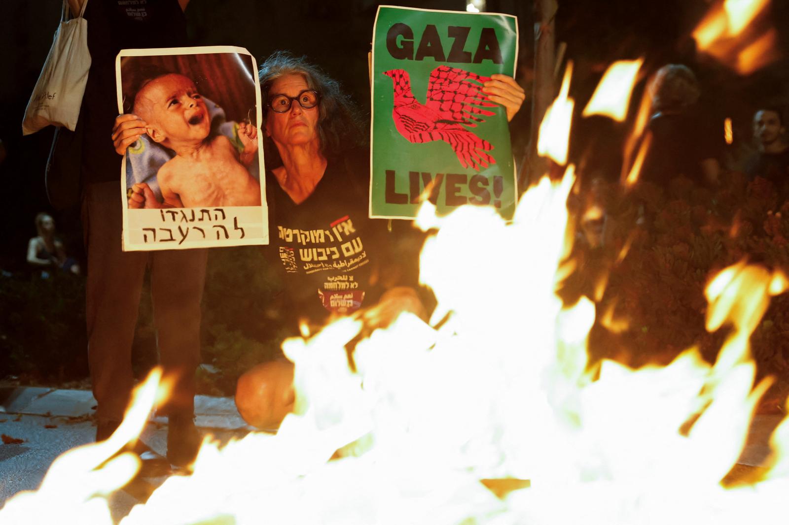 Familiares y simpatizantes de los rehenes israelíes retenidos por Hamás en Gaza portando antorchas, pancartas y fotos de los rehenes protestan frente a la oficina del primer ministro israelí durante una sesión del gabinete de seguridad.