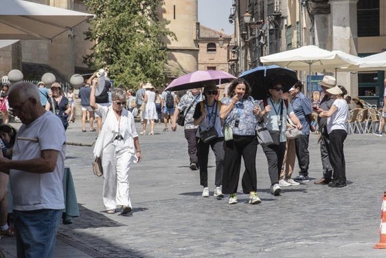 varias personas se protegen del sol con apraguas.