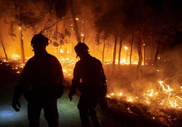Dos bomberos trabajan para impedir que el incendio se propague