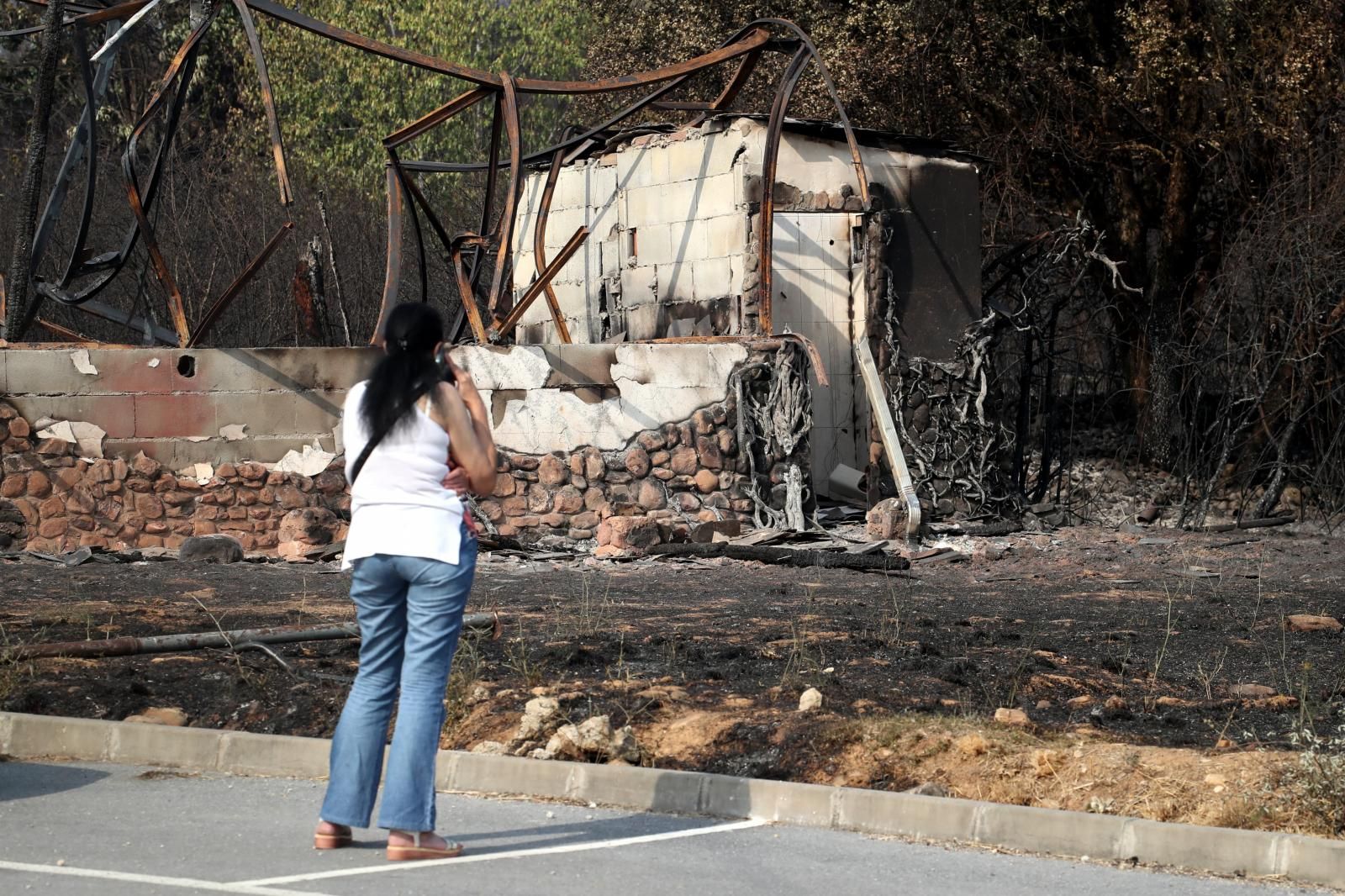 Mujer contempla un edificio calcinado por las llamas del incendio que ha afectado la localidad leonesa de Yeres