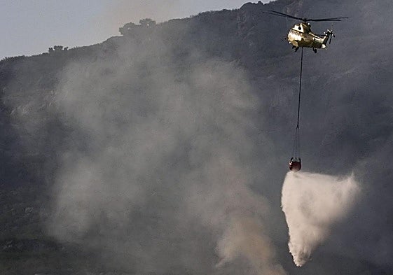 Un helicóptero trabaja en las labores de extinción del incendio que afecta a la Sierra de la Plata, en Tarifa (Cádiz)
