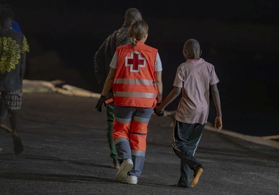 Una trabajadora de Cruz da la mano a un menor llegado en un cayuco a El Hierro.