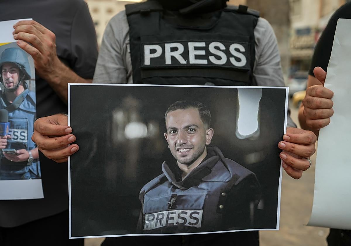 Un periodista sirio sostiene una fotografía de un periodista palestino fallecido.