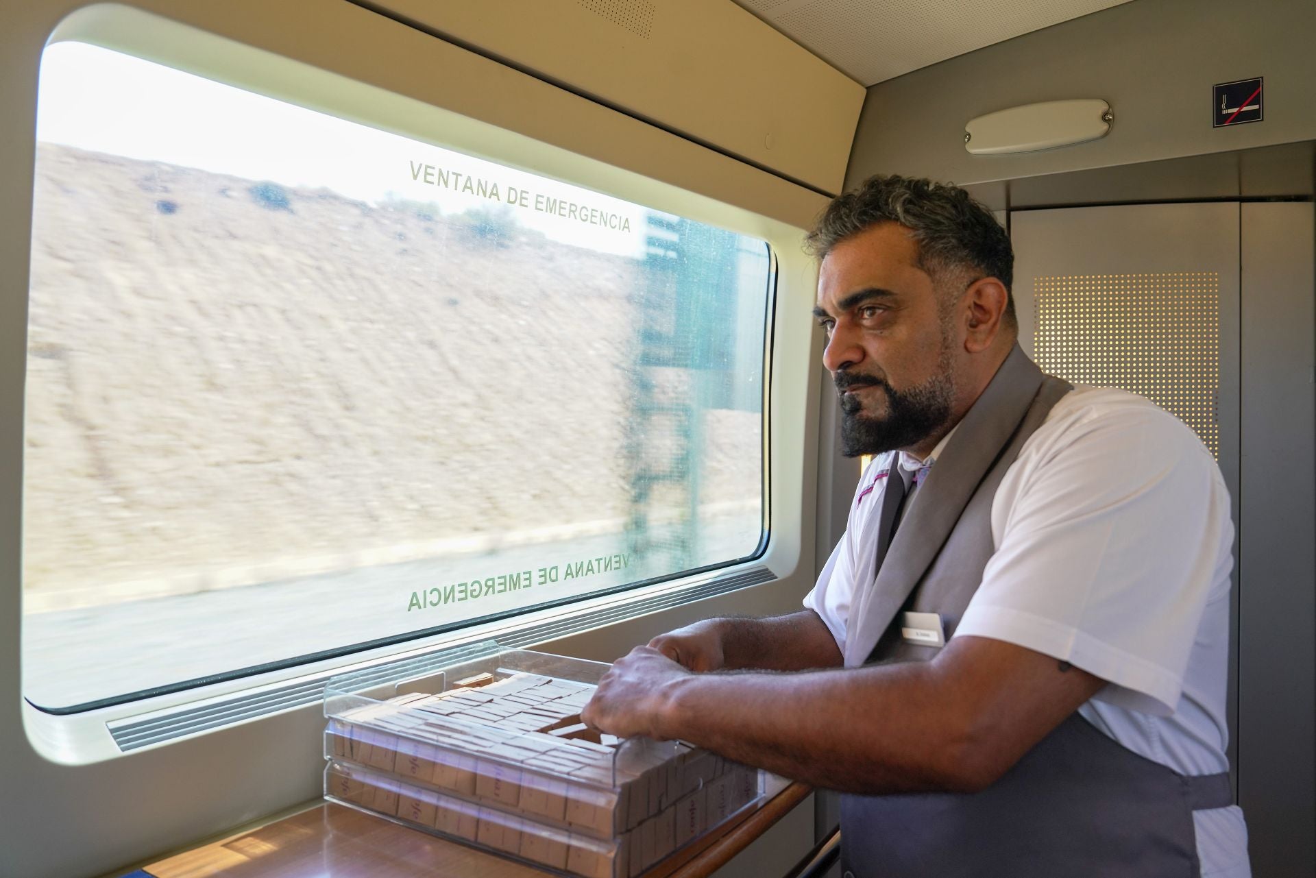 Roberto, personal del servicio de a bordo, mira por la ventanilla del tren.