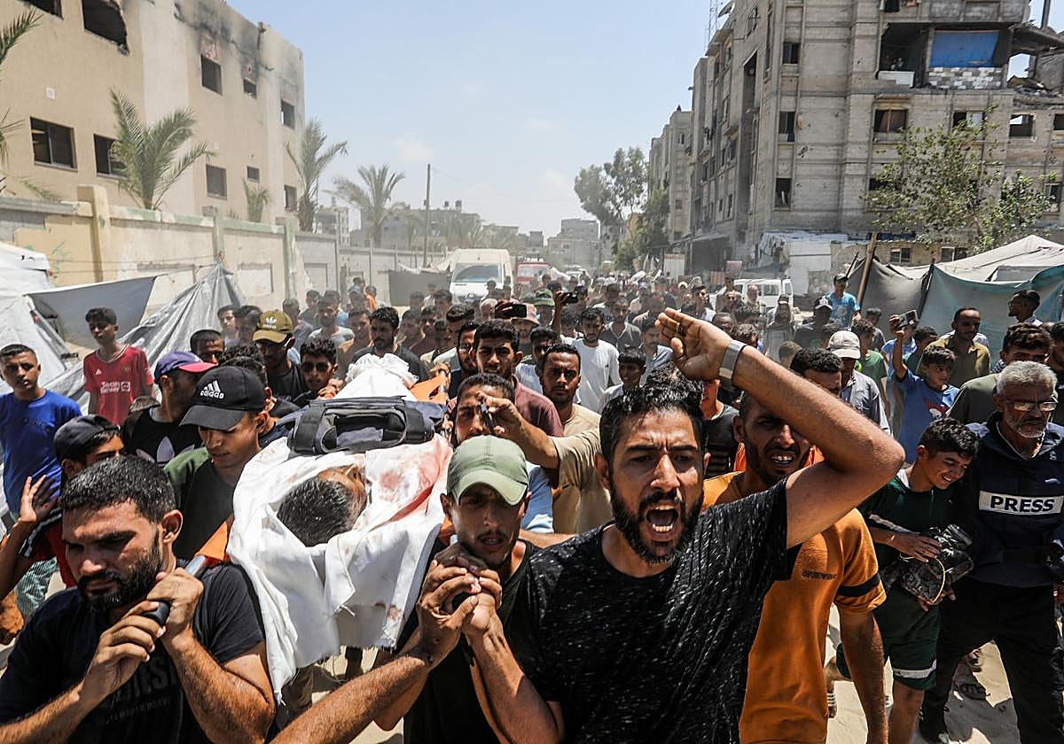 Palestinos transportan el cadáver de un periodista asesinado en el ataque israelí contra el hospital Al Nasser de Jan Younis.