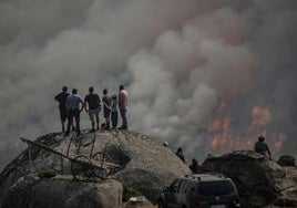 Varias personas observan un incendio forestal declarado este lunes.