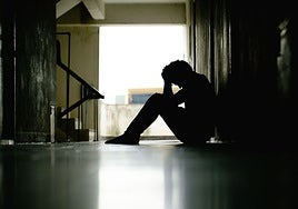 Silueta de un hombre deprimido sentado en el suelo.