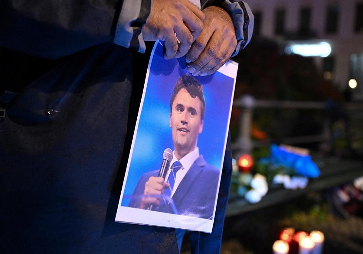 Un hombre sostiene un retrato de Charlie Kirk durante una vigilia.