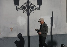 Hombre jubilado pasea por la calle con periódico en mano.