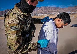 Un agente lleva a un migrante esposado en la base de Guantánamo.