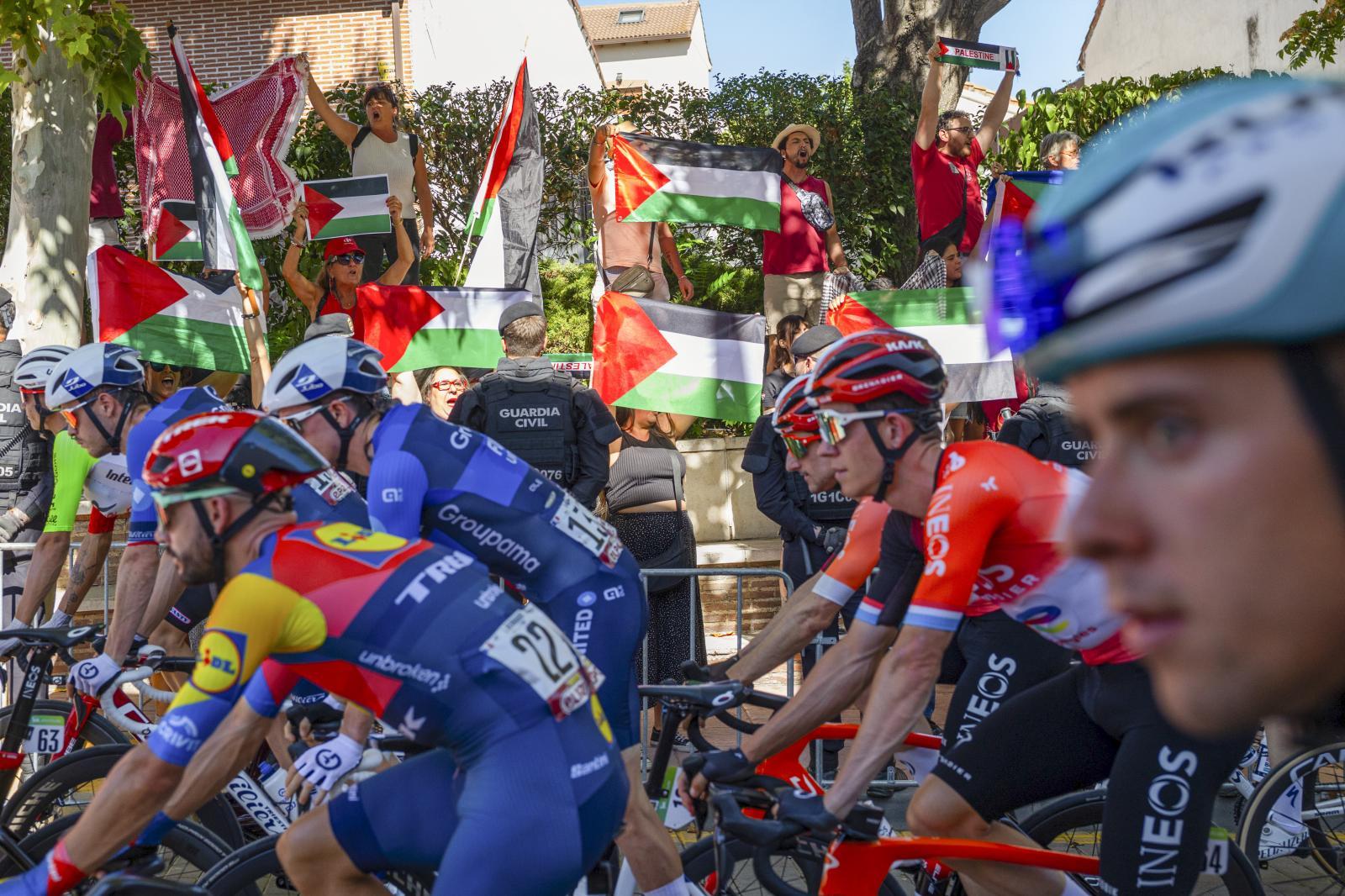 El pelotón ciclista pasa delante de la manifestación propalestina