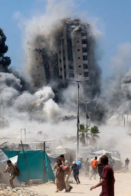 Un grupo de palestinos huye mientras se derrumba una torre de edificios en Ciudad de Gaza al ser alcanzada por un bombardeo israelí.