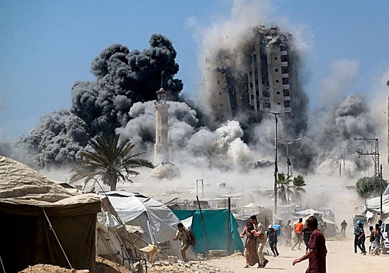 Un grupo de palestinos huye mientras se derrumba una torre de edificios en Ciudad de Gaza al ser alcanzada por un bombardeo israelí.