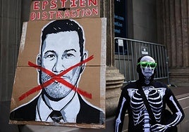 Un manifestante vestido con un traje de esqueleto junto a un cartel de Jimmy Kimmel durante una protesta por el despido del presentador.