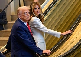 Trump y Melania observan a los medios al pararse la escalera.