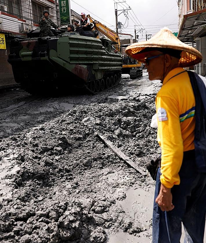 Imagen secundaria 2 - Un hombre sostiene a su perro mientras camina por una calle de Macao; sacos de arena se apilan frente a un restaurante en Hong Kong y el lodo cubre una céntrica arteria de Hualien (Taiwán).